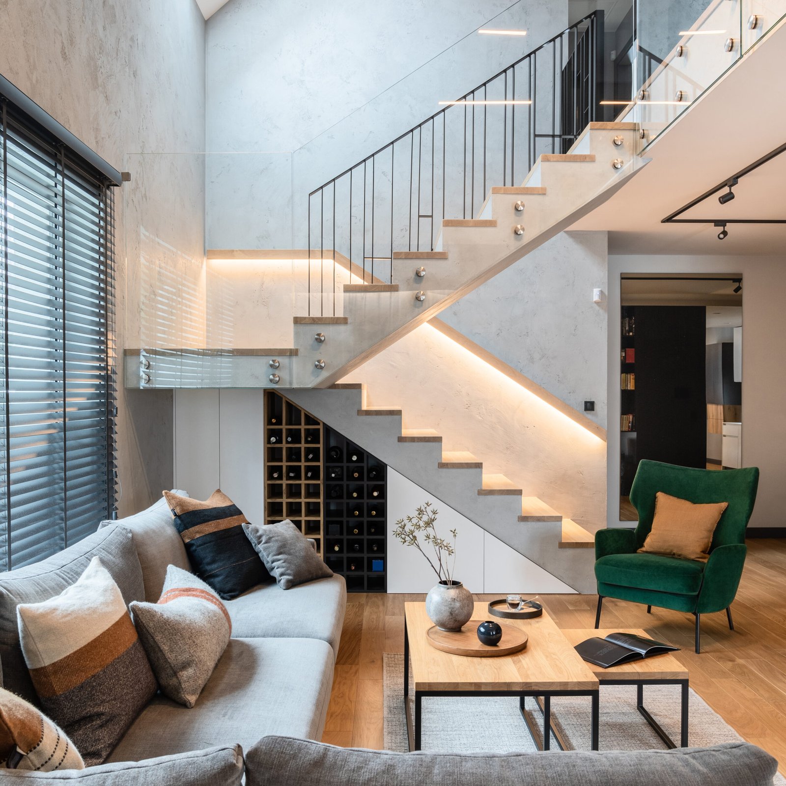 Stylish composition of stairs in living room interior. Grey sofa, green velvet armchair, coffee table and minimalist personal accessories. Modern home decor. Template.